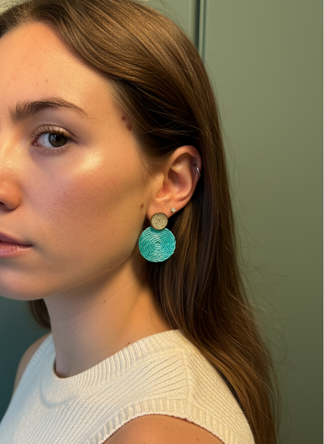 Woman wearing turquoise earrings against a neutral background