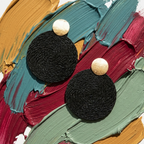 Black earrings on a colorful abstract background