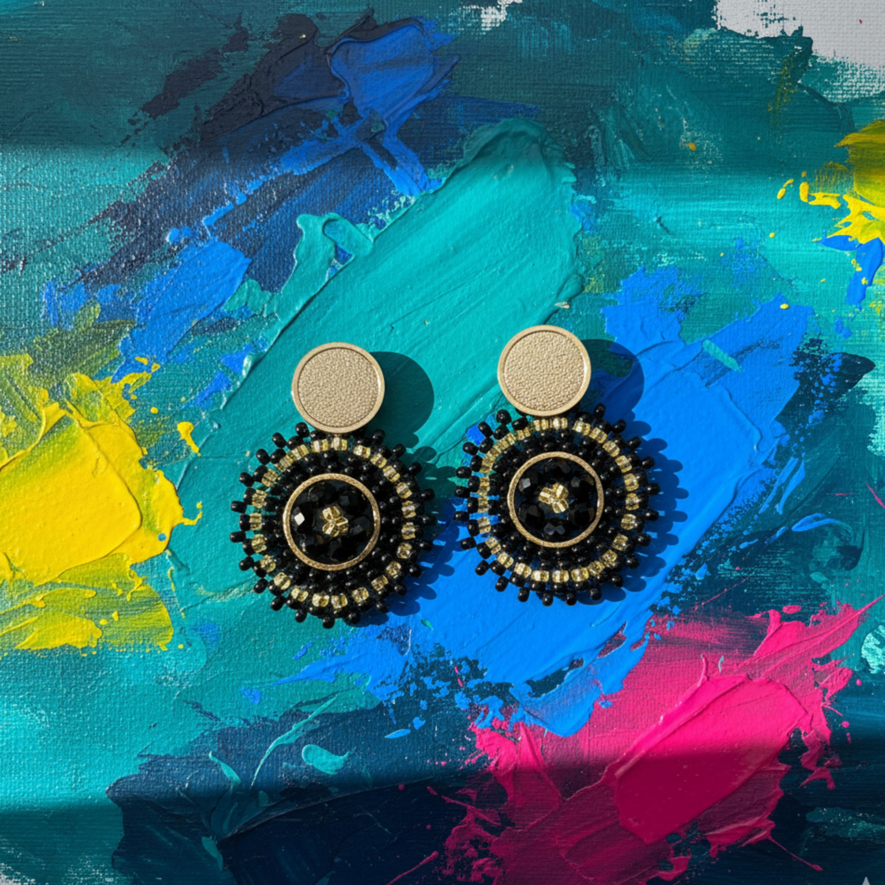 Pair of black Manila earrings on a colorful abstract painting background
