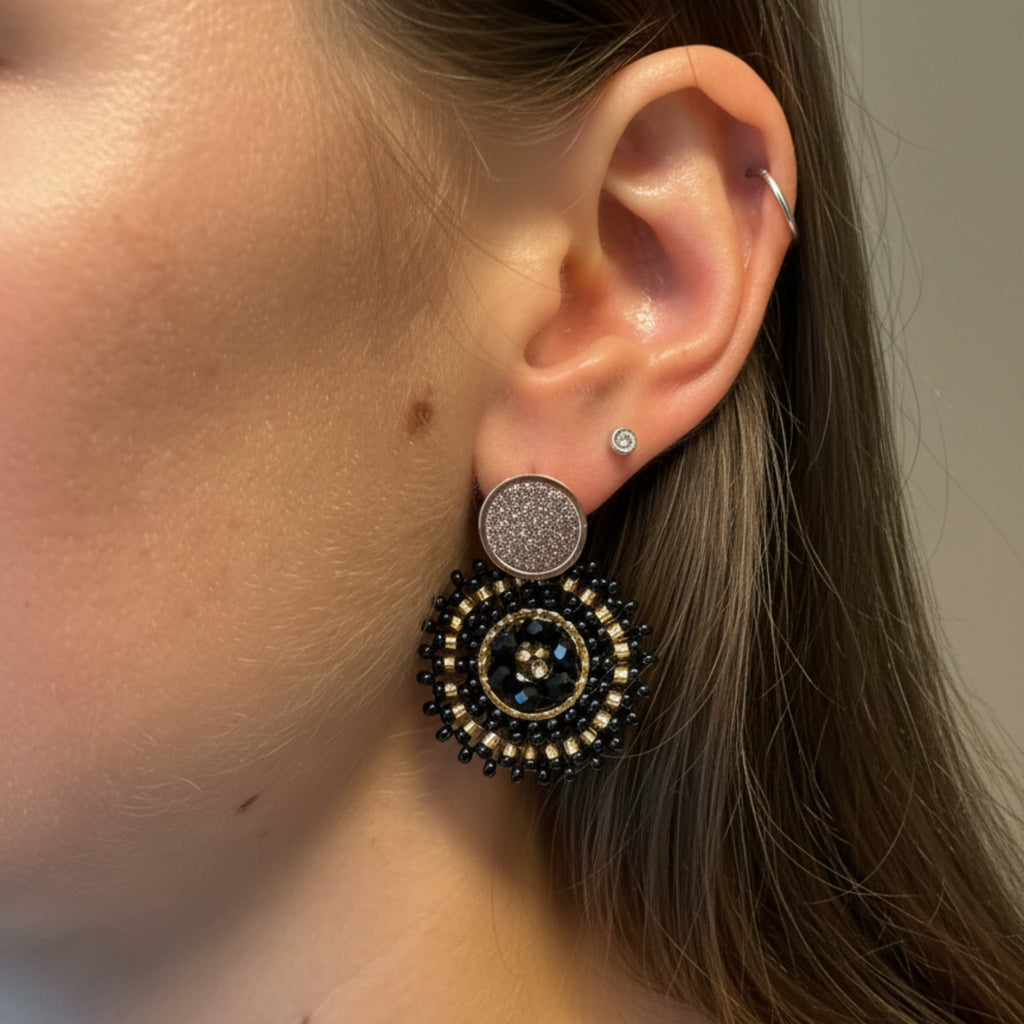 Close-up of a person wearing black Manila earring with a neutral background