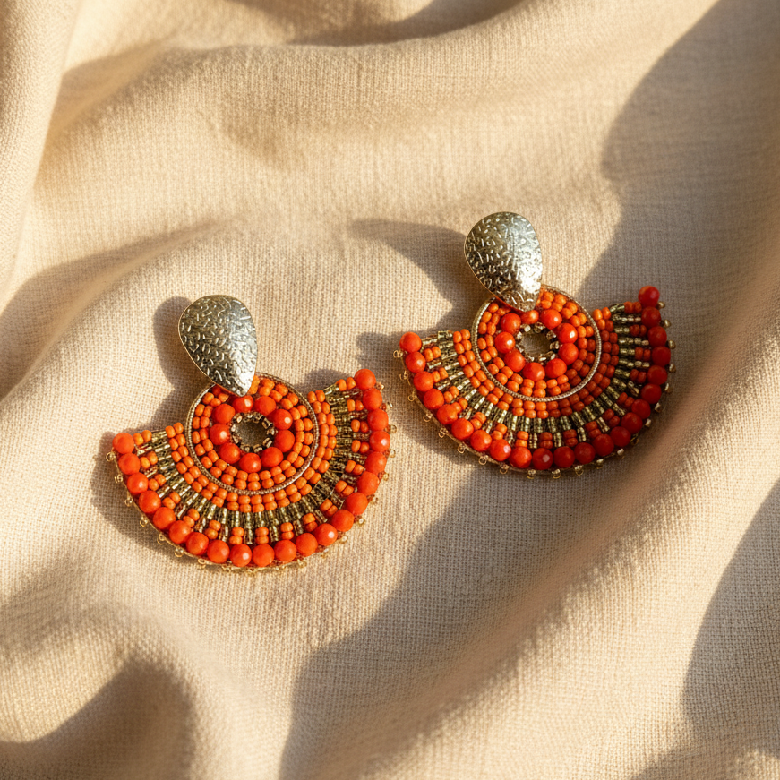 Pair of orange beaded earrings on beige fabric