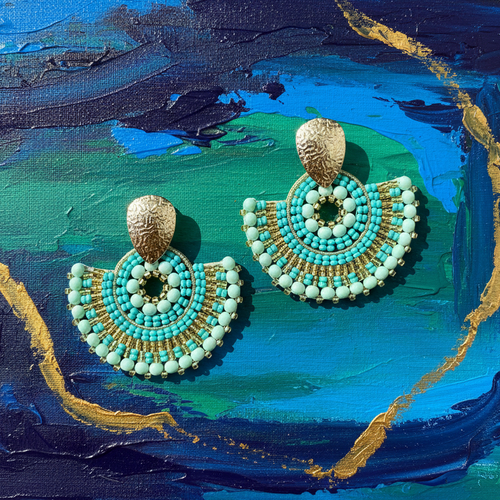 Turquoise and gold earrings on a textured blue and green background