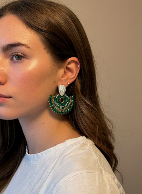 Woman wearing green earrings against a neutral background