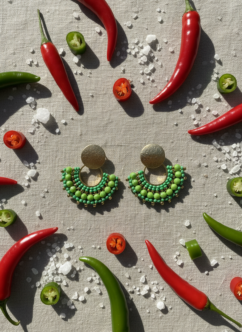 Light green ebaded earrings on a soft linen tablecloth with peppers and salt