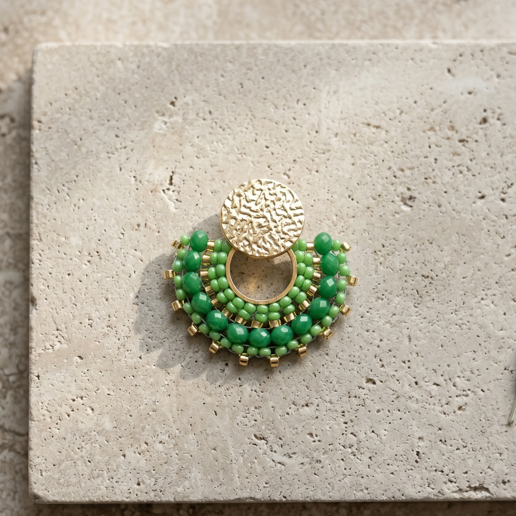Green ebaded earrings on stone surface