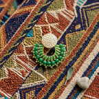 Green beaded earring on textile surface