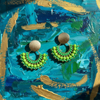 Green beaded earrings on a textured blue and gold background
