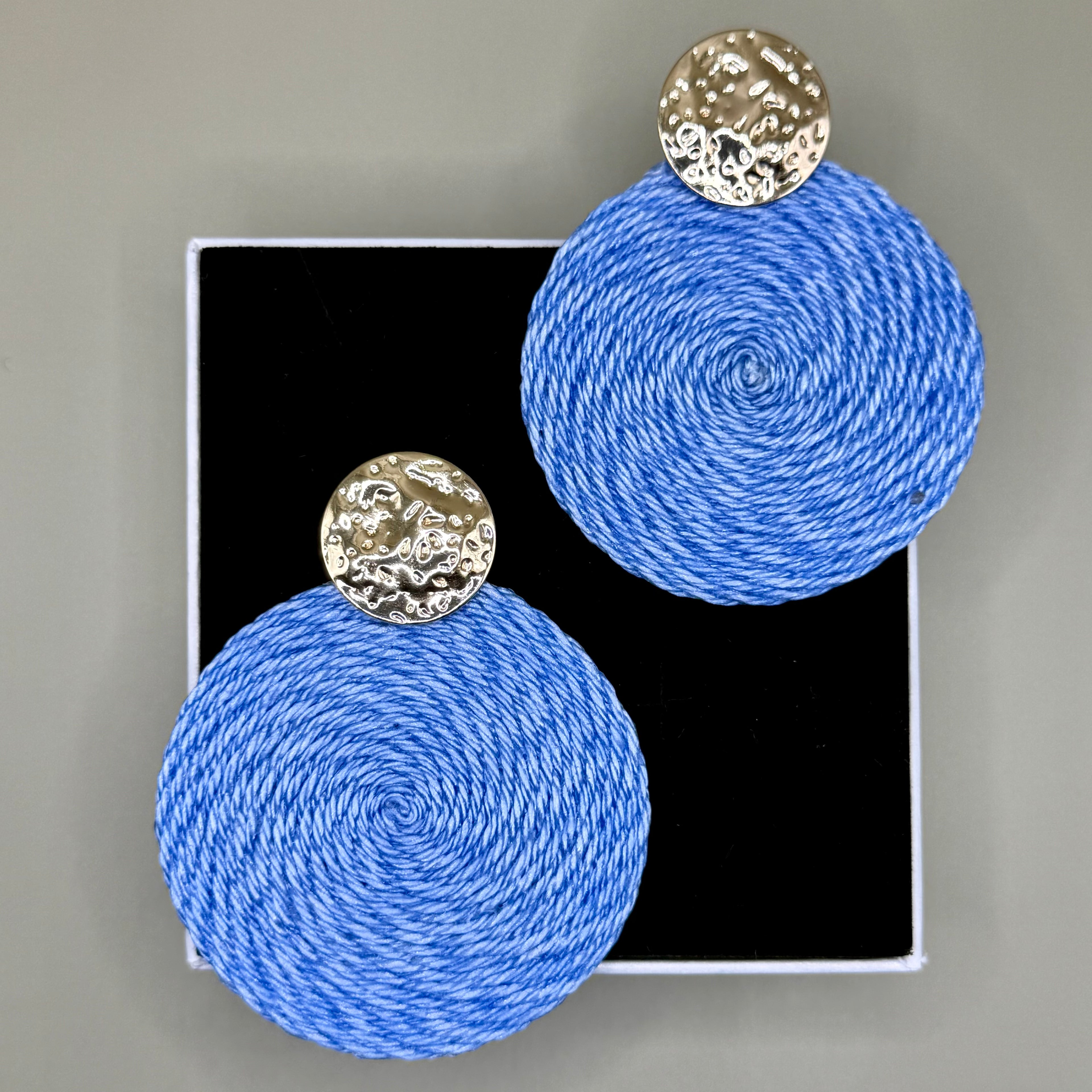 Blue spherical earrings with gold circular tops on a gray background