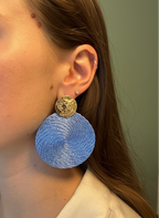 Close-up of a person wearing blue earrings with gold accents.