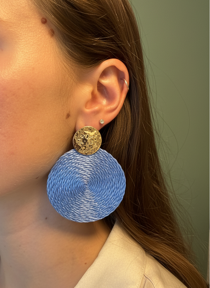 Close-up of a person wearing blue earrings with gold accents.