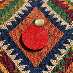 Red earrings on a colorful patterned fabric background