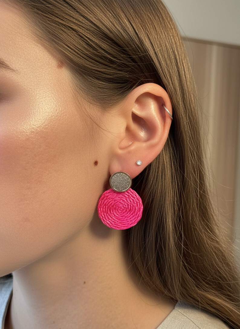 Close-up of a person wearing pink earrings with a neutral background