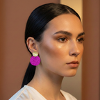 Woman wearing a magenta round earring against a neutral background