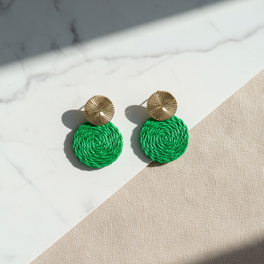 Green round earrings with gold tops on a marble surface