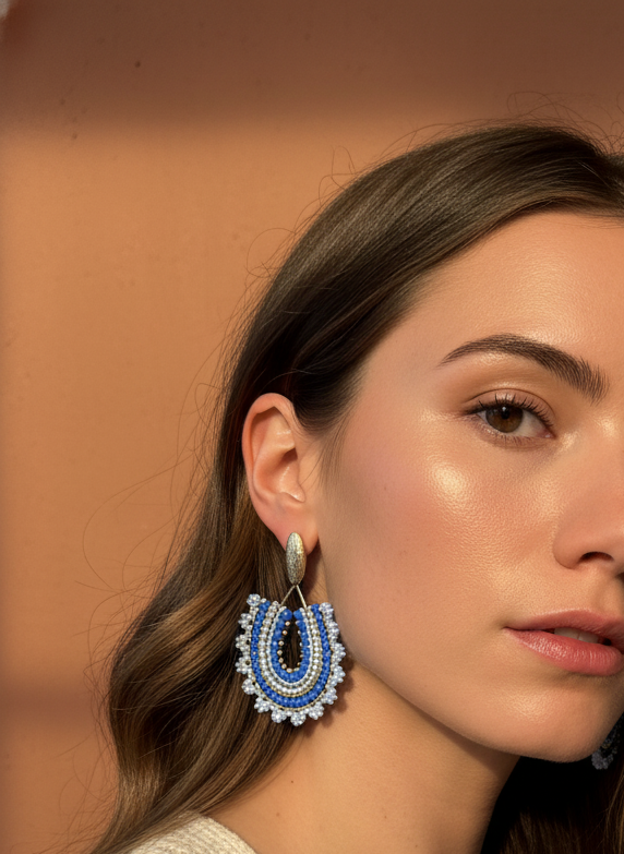 Woman wearing blue and white floral earrings against a warm-toned background