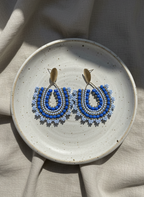 Blue beaded earrings on a ceramic plate with a neutral background