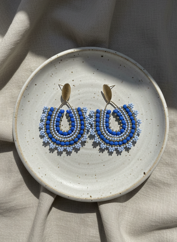 Blue beaded earrings on a ceramic plate with a neutral background