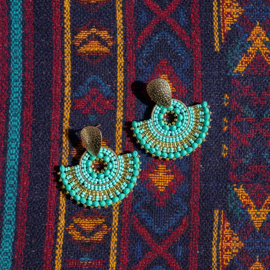 Light blue beaded earrings on a patterned fabric background