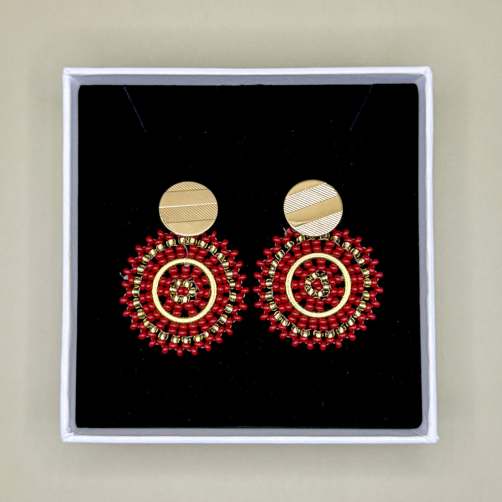 Pair of red beaded earrings in a black box with a beige background