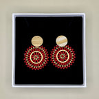 Pair of red beaded earrings in a black box with a beige background