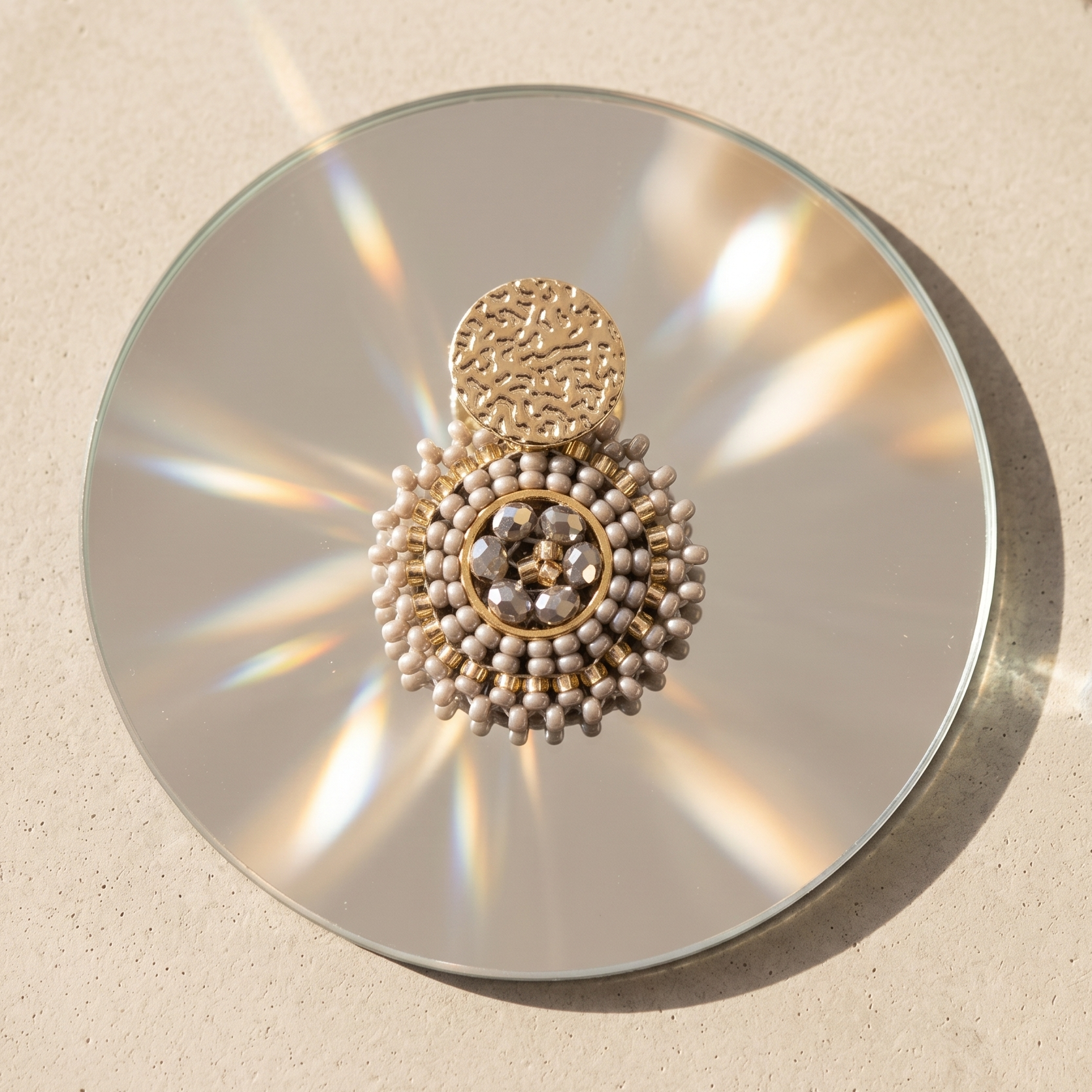Statement earring on a round mirror with a textured beige background
