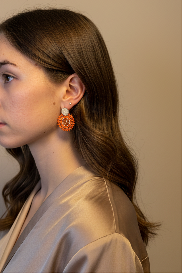 Woman wearing orange earrings against a plain background