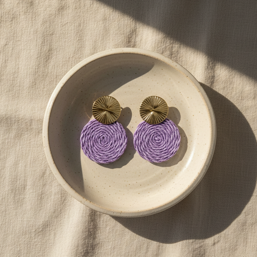 Pair of purple earrings with gold tops on a beige plate.