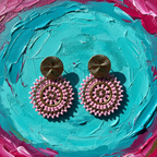 Pink and gold earrings on a textured blue and pink background