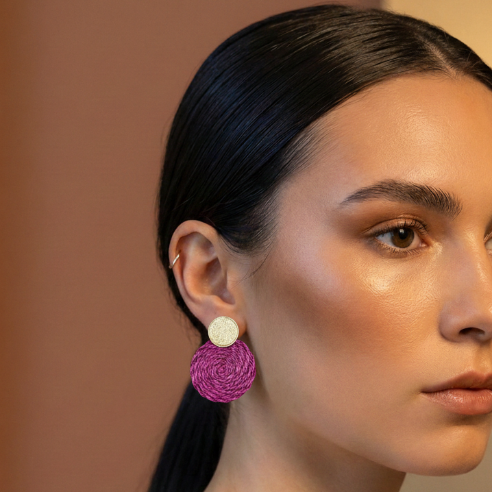 Woman wearing plum round textile earrings with a neutral background