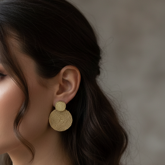 Woman with black hair wearing round textile beige earrings
