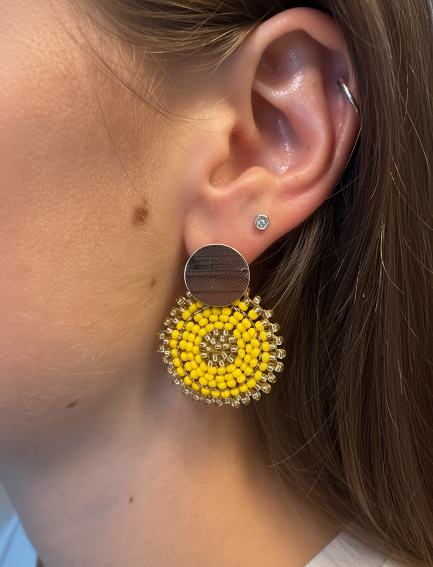 Close-up of an ear wearing a yellow Manila earring